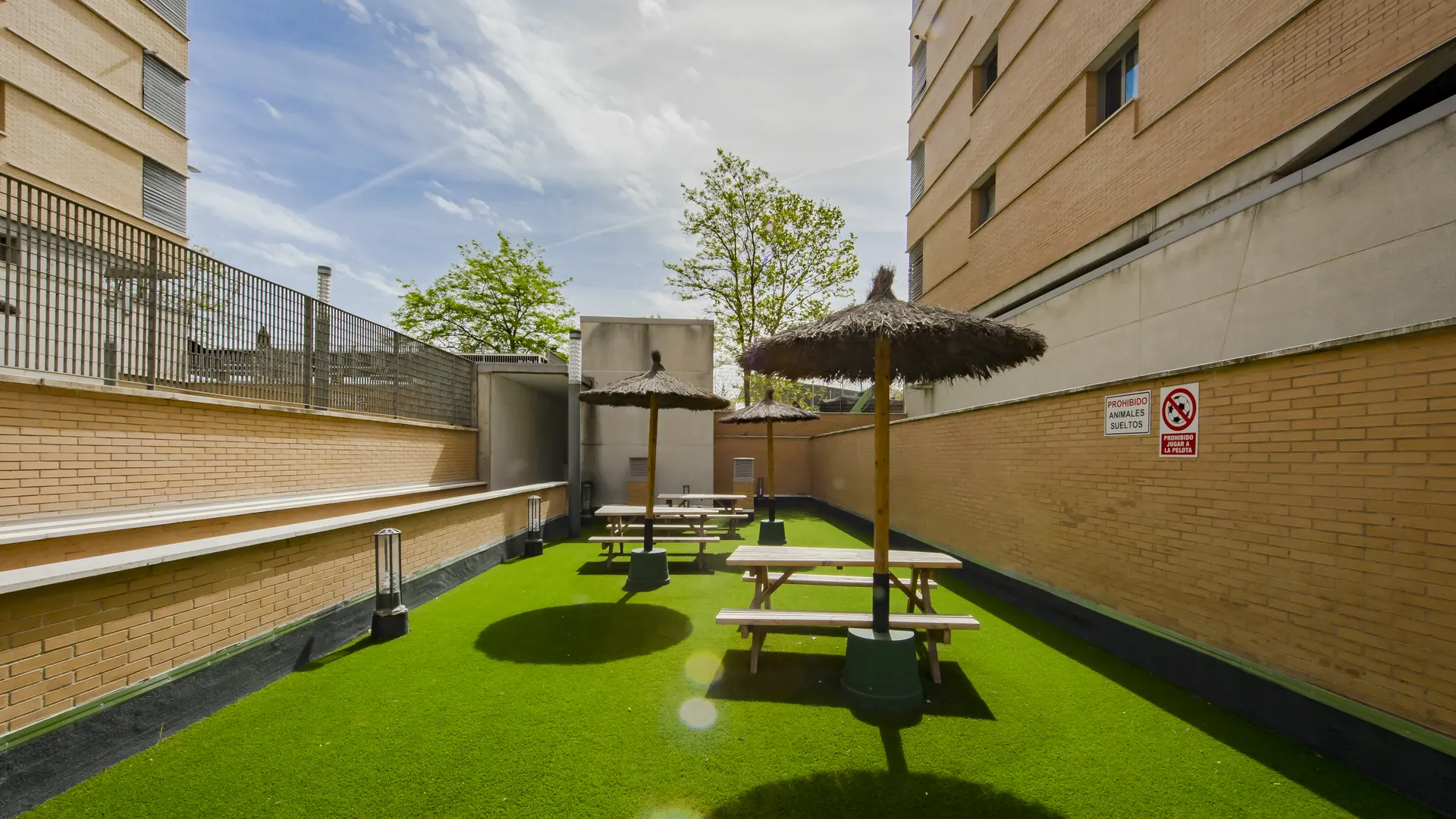 Zona de merendero de la urbanización con mesas y sombrillas